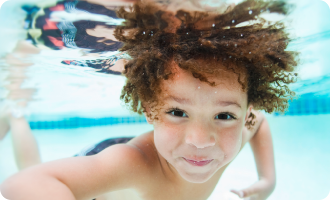 younger boy underwater in pool with eyes open